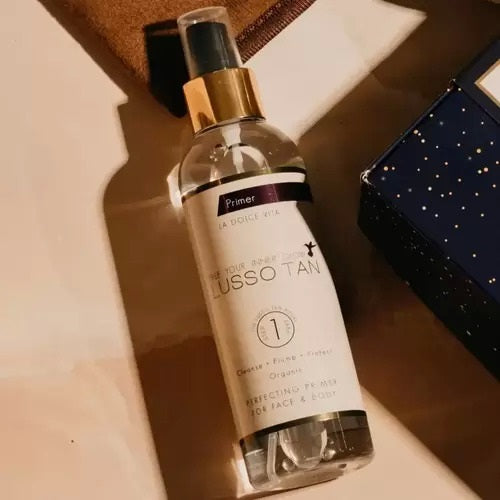 Lusso Tan primer bottle on a surface with a blurred background