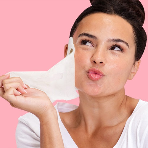 Woman applying Skin Republic Spots and Blemish Face Mask to her face with a pink background