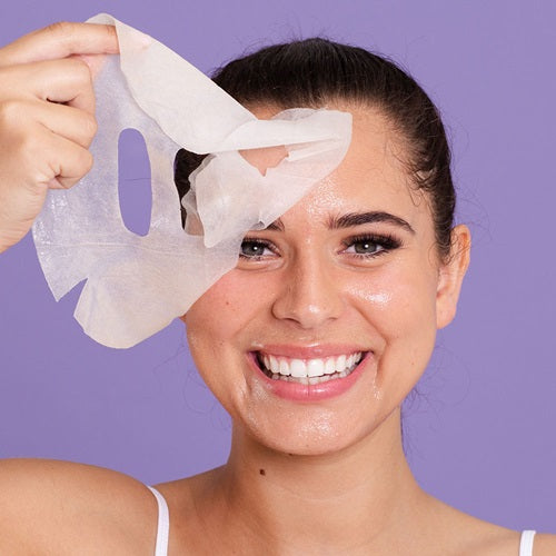 Woman applying a Skin Republic Vitamin C face mask with a purple background