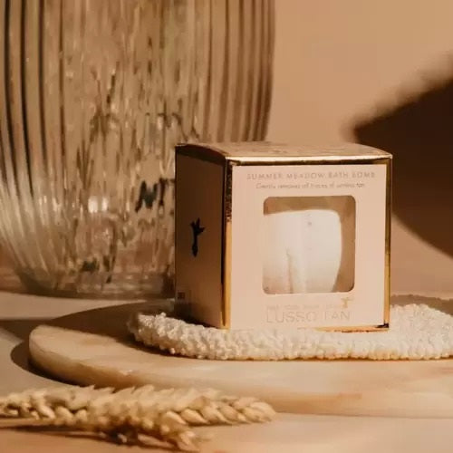 Lusso tan removing bath bomb packaging on a wooden surface with a textured wall in the background